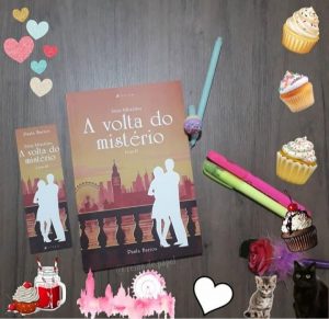 Capa do livro "A volta do mistério" ao lado do marcador do livro. No lado direito 2 marcadores de texto (rosa e verde) e uma caneta com tampa de cupcake. Ao redor formando uma moldura há vários cupcakes e corações. No canto inferior direito dois gatinhos.
